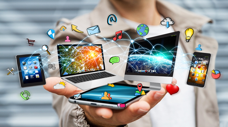 Person holds multiple connected devices—a laptop, tablet, and smartphones—with floating app icons and glowing network lines, illustrating digital connectivity and cloud computing.